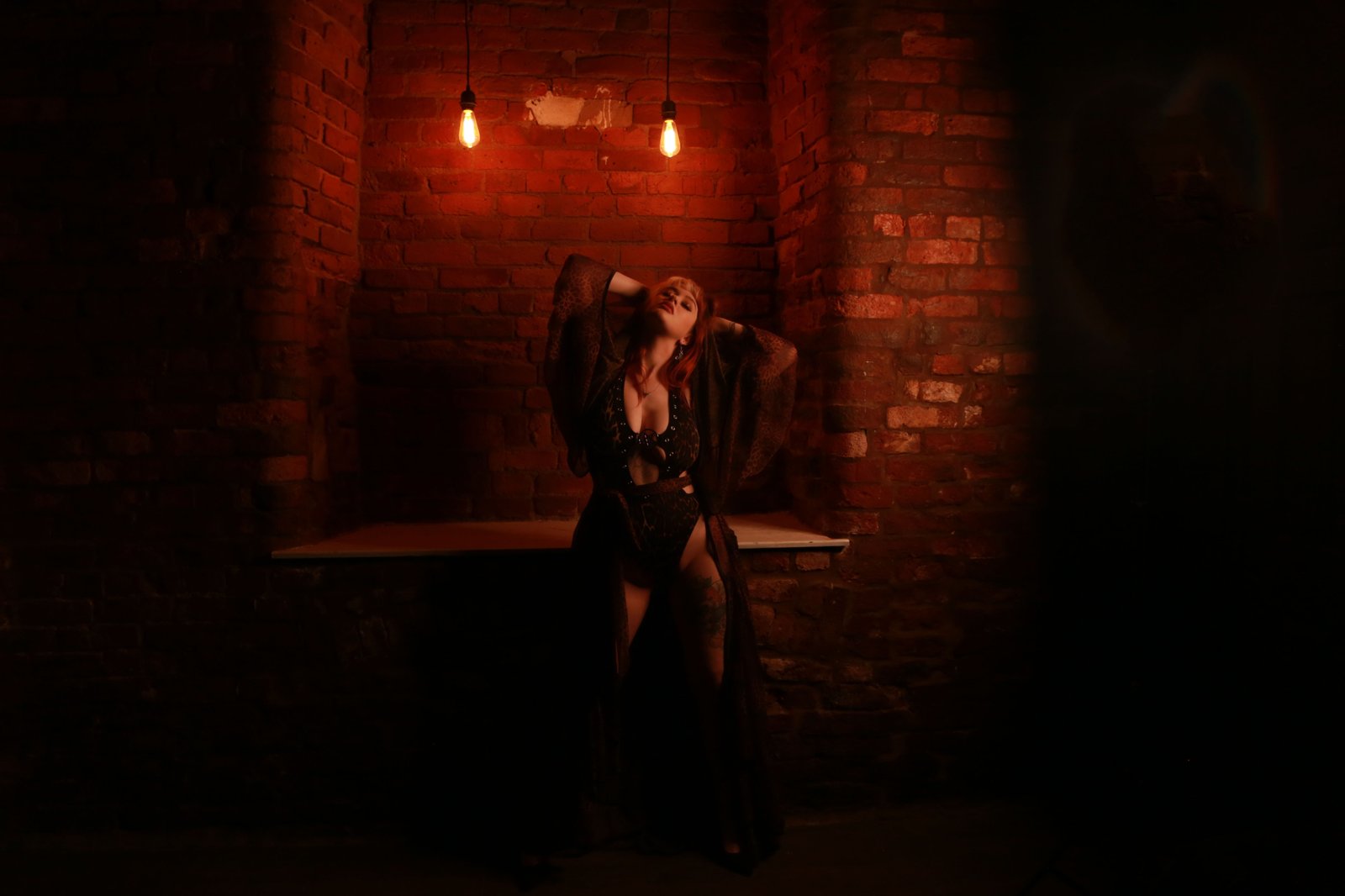 woman posing for a boudoir photoshoot in front of brick wall